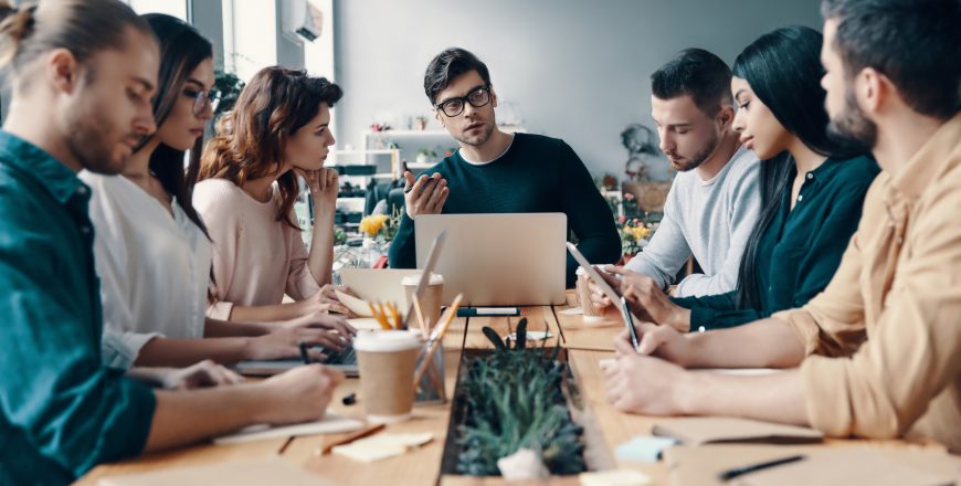 Leadership. Group of young modern people in smart casual wear discussing something while working in the creative office