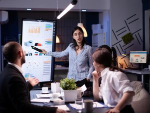 Workaholic focused businesswoman explaining management solution pointing strategy on monitor