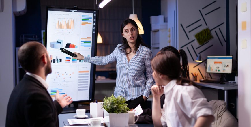 Workaholic focused businesswoman explaining management solution pointing strategy on monitor